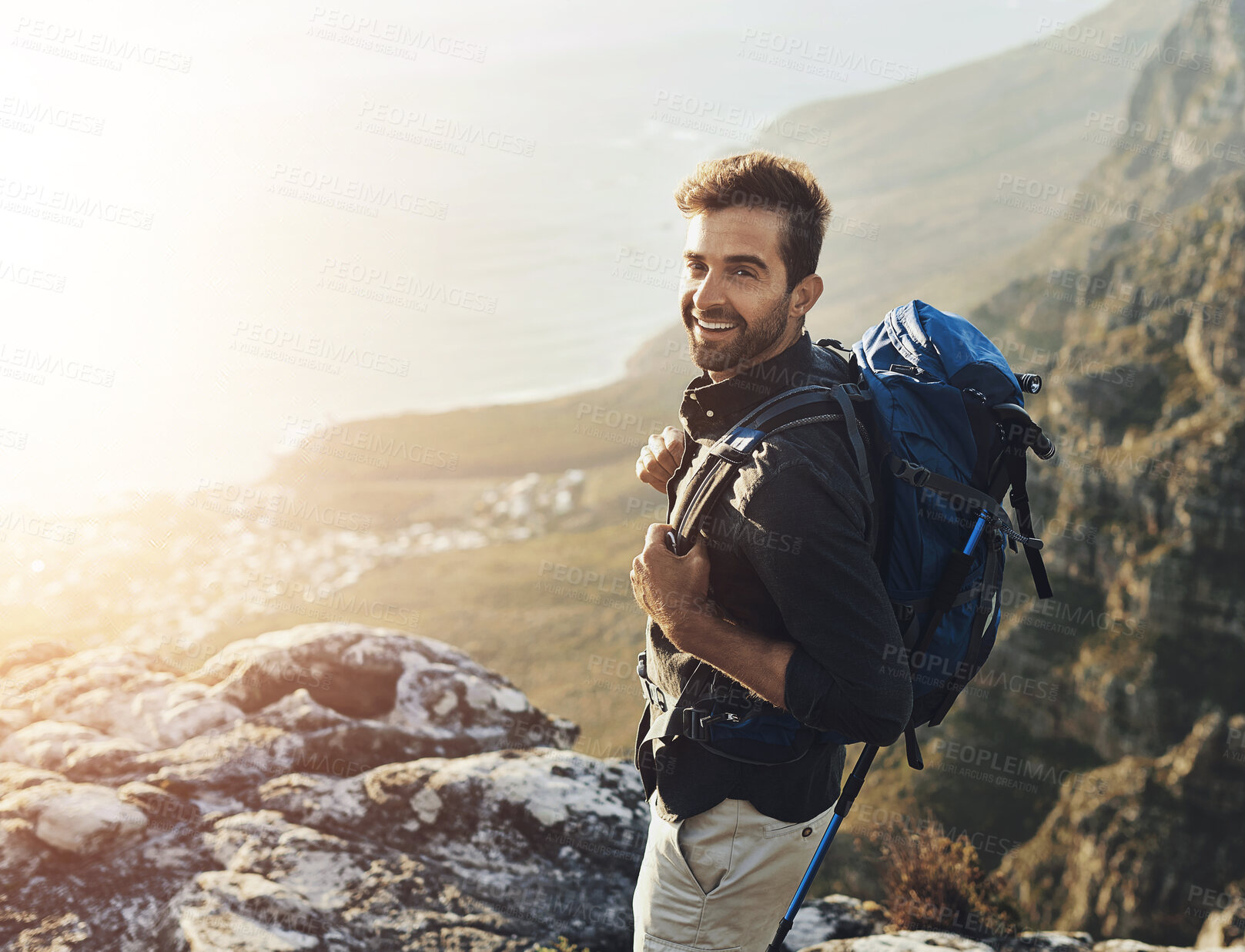 Buy stock photo Portrait, mountains and hiking with man, smile and journey with nature, sunshine and getaway trip. Hobby, person and hiker with backpack, adventure and environment with happiness, holiday and fitness