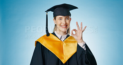 Graduation, okay and student with success in studio for education, learning or college achievement. Portrait of woman with hands or emoji for yes, excellence and certified or good on blue background