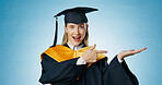 Pointing, graduation and portrait of woman in studio for university, college and academy announcement. Student, presentation and happy person for education, learning and studying on blue background