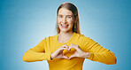 Woman, happy and heart with hands in studio, support and caring emoji in portrait on blue background with mock up. Love, symbol and wellness icon, kindness and charity with female person or empathy