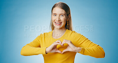 Buy stock photo Woman, happy and heart with hands in studio, support and caring emoji in portrait on blue background with mock up. Love, symbol and wellness icon, kindness and charity with female person or empathy