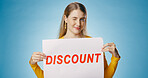 Woman, excited and discount poster in studio for shopping, retail or sale announcement of store or shop. Young person or seller in portrait with sign, wink and news for makeup deal on blue background