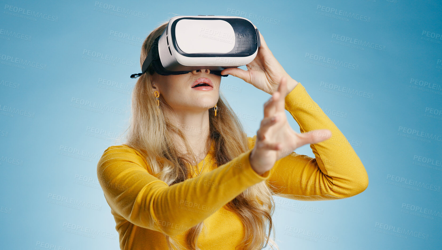 Buy stock photo VR, woman and hand in studio for metaverse, digital and video game on blue background. Technology, virtual and streaming for gamer person, hobby and internet for 3d augmented reality experience