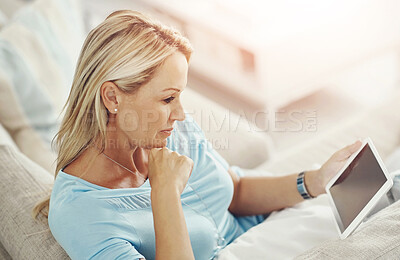 Buy stock photo Woman, tablet and reading on sofa in house with mock up space on screen with app, streaming or ebook in lounge. Mature person, digital touchscreen and relax on couch with movie, film or subscription