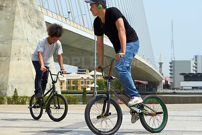 Buy stock photo BMX riders doing tricks out in the city