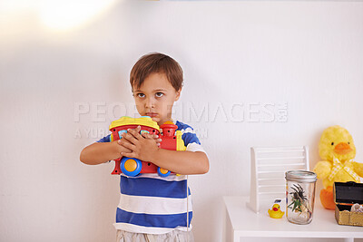 Buy stock photo A young boy possessively clasping his toy truck to his chest