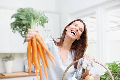 Buy stock photo Happy woman, harvest and fresh carrots in kitchen for meal, preparation and vegetables in basket. Female person, organic produce and nutrition for diet, healthy eating and sustainability in house