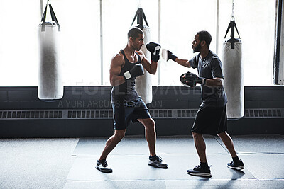 Buy stock photo Shot of a male boxer practising his moves with his coach