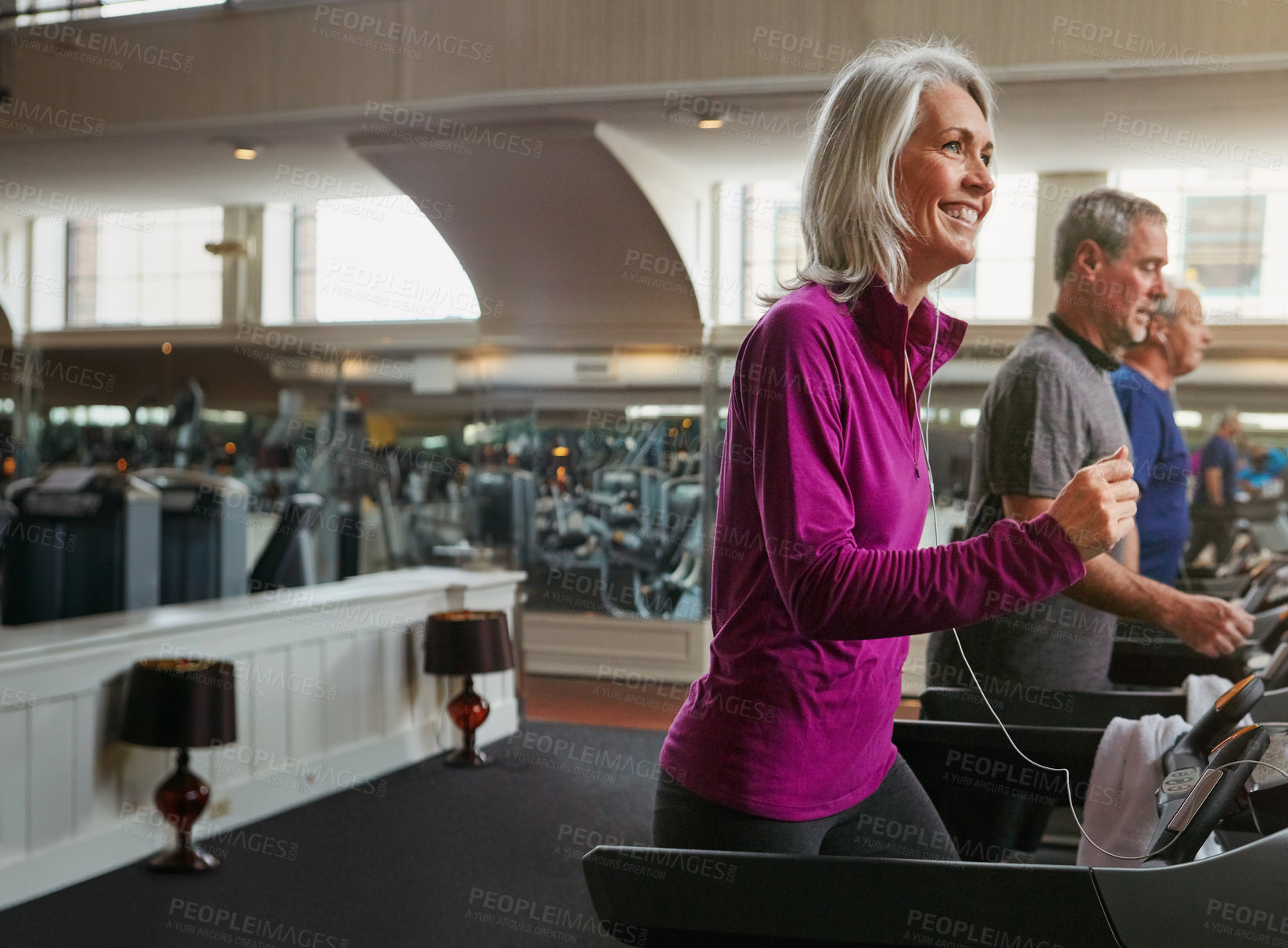 Buy stock photo Fitness, cardio and mature woman on treadmill in gym for health, wellness and body exercise. Smile, earphones and female person listening to music on running equipment for workout in training center.