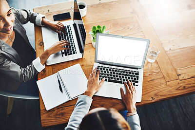 Buy stock photo High angle shot of two businesswomen working on laptops in an office