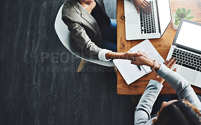 Buy stock photo High angle shot of two businesswomen shaking hands in an office