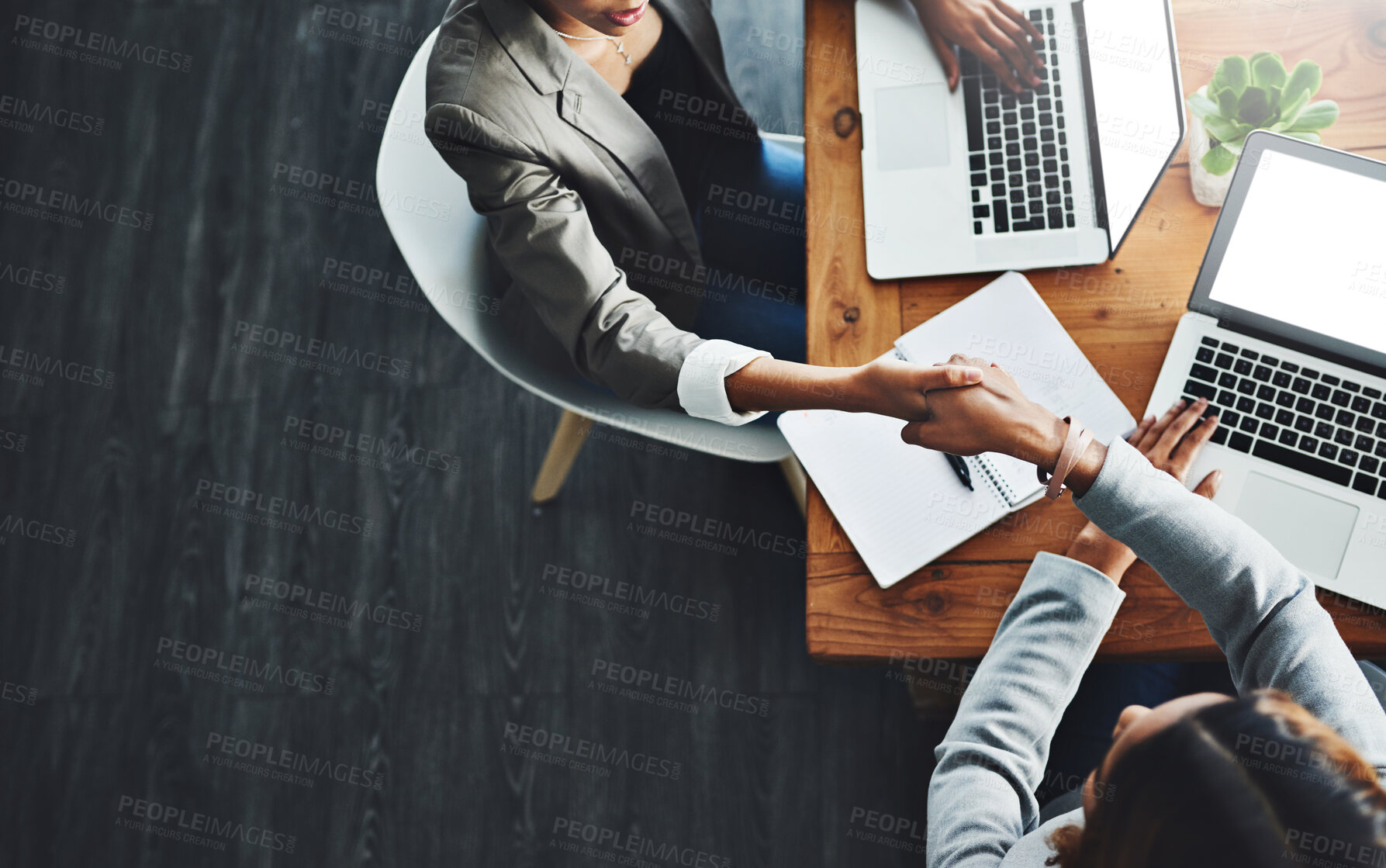 Buy stock photo High angle shot of two businesswomen shaking hands in an office