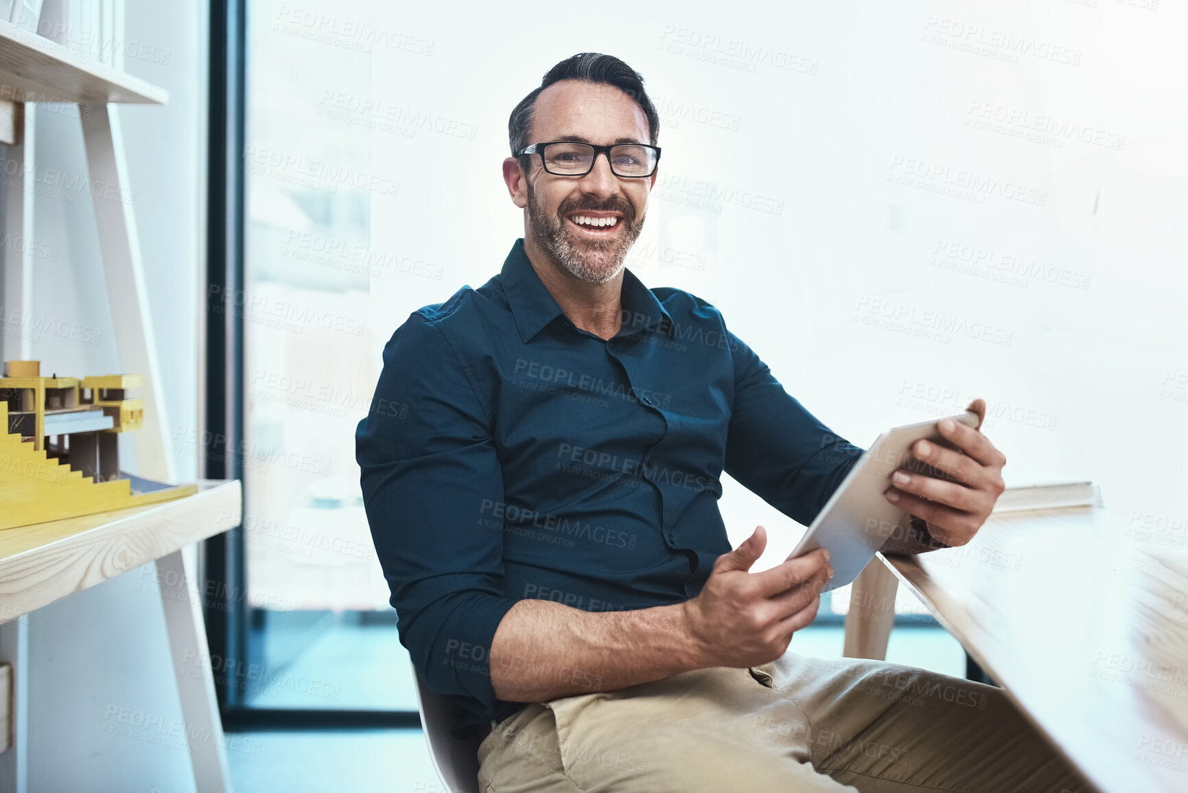 Buy stock photo Shot of a mature businessman using his digital tablet while sitting at his desk