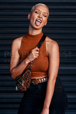 Buy stock photo Young woman, funky and fashion with bag or tongue out for style on an outdoor dark background. Female person or model with stylish clothing or confidence for cool attitude or summer in an urban town