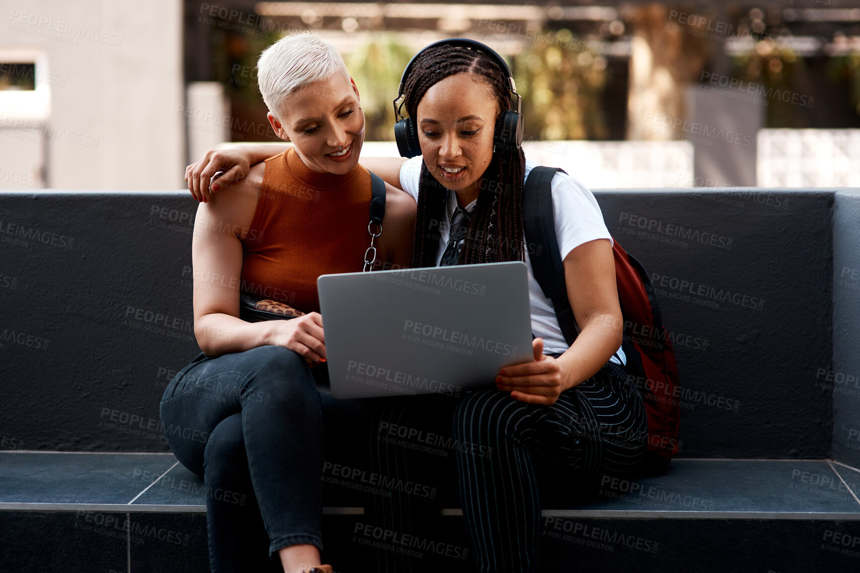 Buy stock photo Women, friends and laptop on bench in city with reading, smile and relax on metro sidewalk with social media. People, students and computer with embrace, research or streaming video on web in street