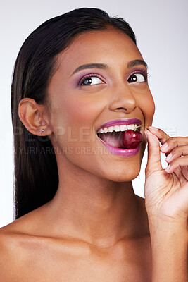 Buy stock photo Cherry, eating and woman in studio for makeup, nutrition and thinking on white background. Indian girl, fruit and playful with cosmetics for beauty aesthetic, eco friendly skincare and wellness