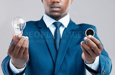 Buy stock photo Idea, light bulb and coin in studio with businessman, choice and vision on gray background. Corporate, black man and technology in hands for innovation, investment and sustainability in industry