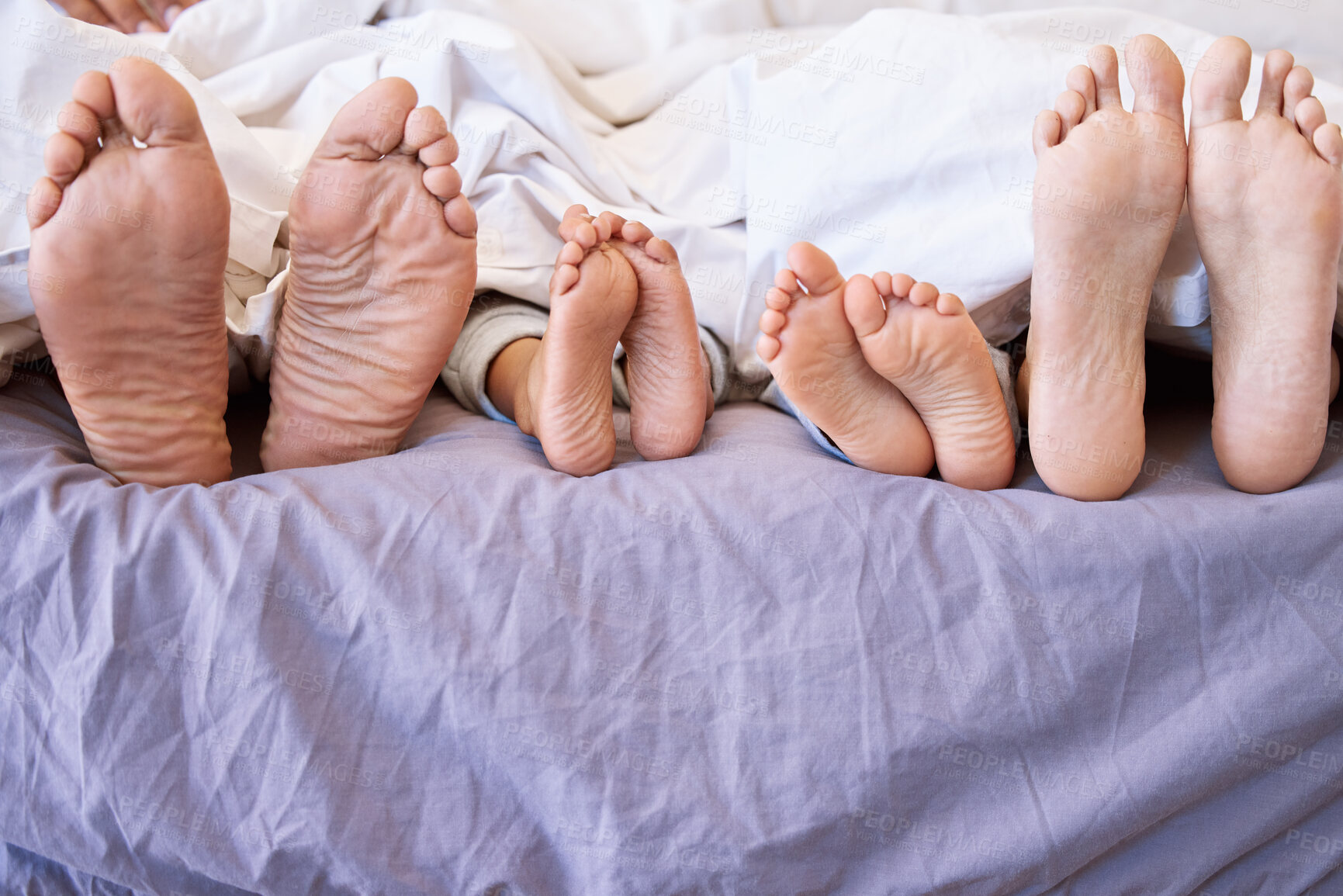 Buy stock photo Family, feet and relax in bed for love, comfortable and connection or security in home for bonding. Parents, children and rest in bedroom on morning for peace, closeup and together for sleeping