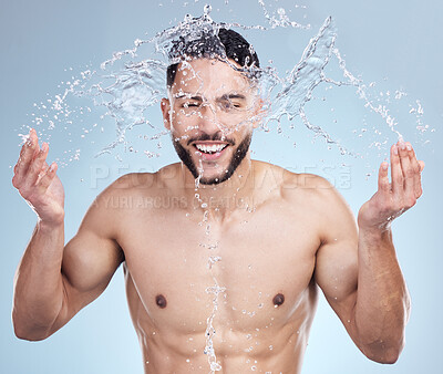 Buy stock photo Water, splash and man with smile for skincare, grooming and  and fresh morning routine on blue background. Health, wellness and happy male person in shower for cleaning, washing and relax in studio.