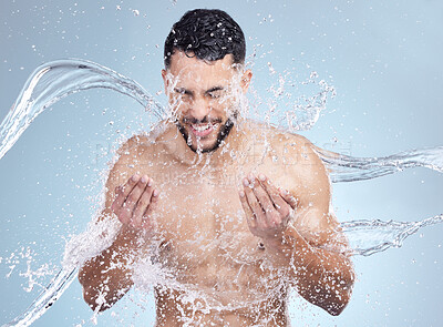 Buy stock photo Water splash, face and man with smile for skincare, fresh morning routine and blue background. Health, wellness and happy male person in shower for cleaning, washing and facial care in studio