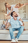 Happy parents and cute daughter at home. Adorable caucasian girl smiling and sitting on father's shoulders with arms outstretched pretending to fly. Young parents enjoying free time with their child