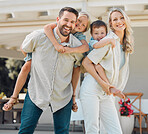 Portrait of happy parents giving their little children piggyback rides outside in a garden. Smiling caucasian couple bonding with their adorable son and daughter in the backyard. Playful kids enjoying