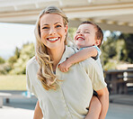 Happy single mother giving her little son a piggyback ride outside in a garden. Smiling caucasian single parent bonding with her adorable child in the backyard. Playful kid enjoying free time with mom