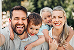 Portrait of happy parents giving their little children piggyback rides outside in a garden. Smiling caucasian couple bonding with their adorable son and daughter in the backyard. Playful kids enjoying