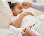 Sick little girl in bed while her mother uses a thermometer to check her temperature. Mixed race parent feeling daughter's forehead. Hispanic child feeling ill and sleeping while mother checks fever