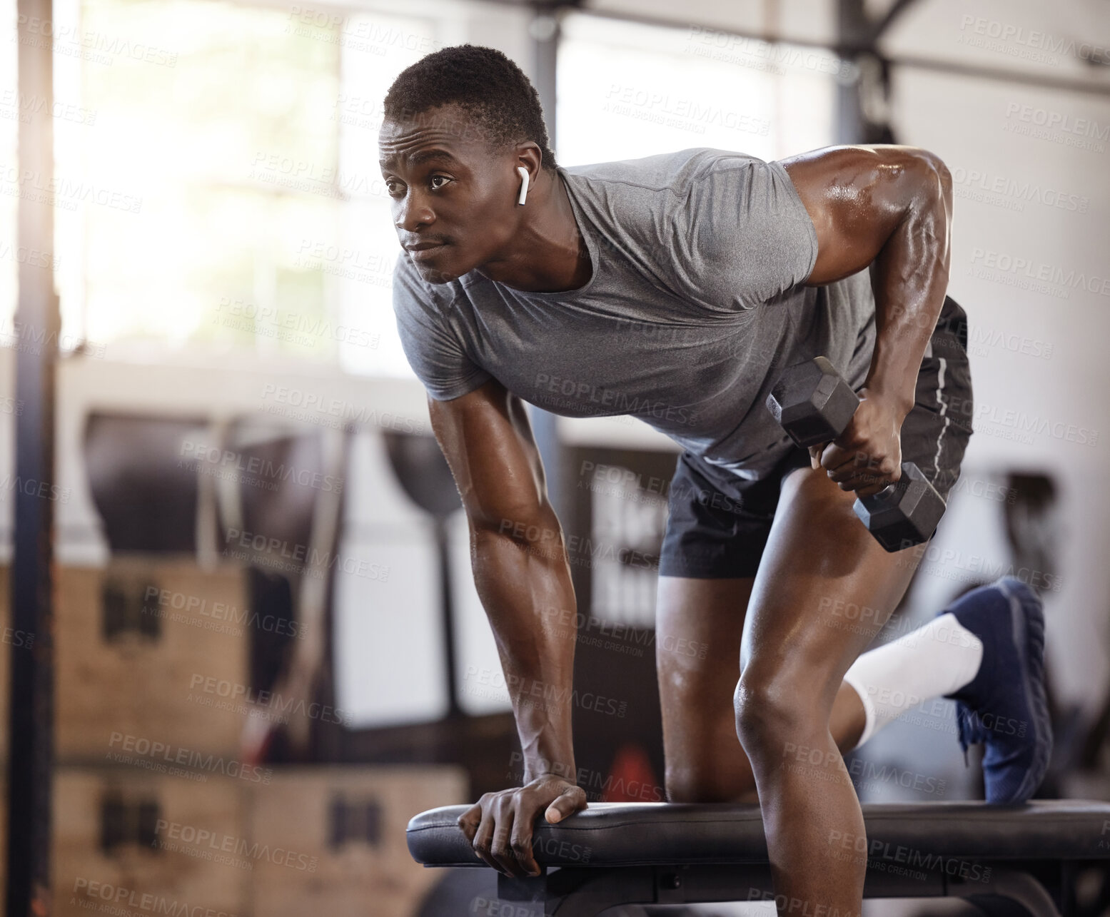 Buy stock photo Dumbbells, bench and exercise with a black man at gym for fitness, training workout and strong muscle. African bodybuilder person with weights for power, focus or performance with earphones for music