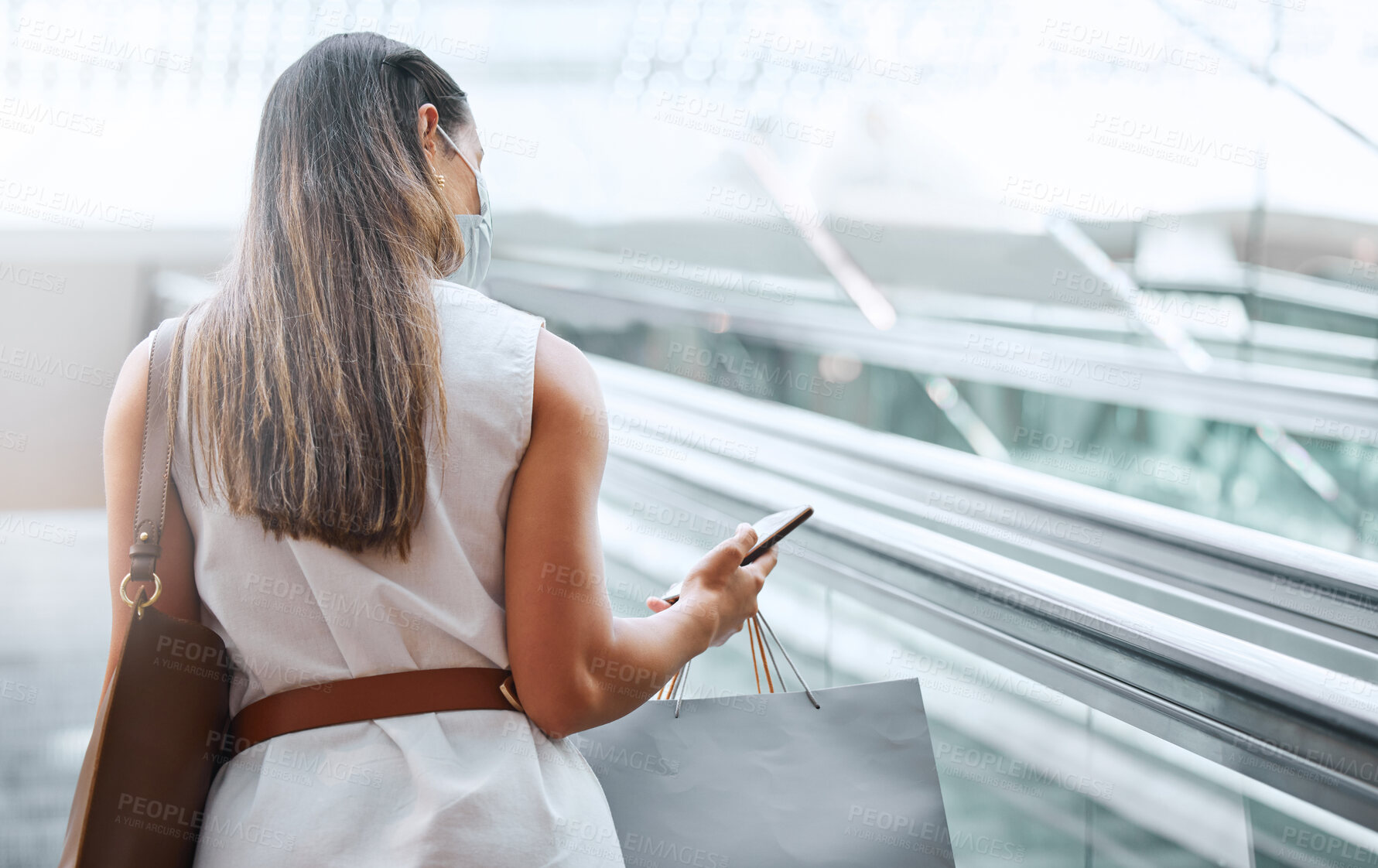 Buy stock photo Shopper, smartphone and back of woman in mall for retail therapy, text and online banking on escalator. Female customer, shopping bag and tech for communication for update, social media and sale