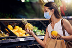 Shopping, holding and looking at fruit at shop, wearing mask for safety and protecting from covid at a grocery store. Young woman buying healthy produce, choosing items and examining at market