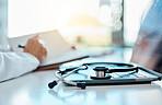 A medical stethoscope lying on a laptop in a doctors office. Hand of a medical professional writing notes in a diary, planning and setting a schedule for appointments. A doctor writing prescriptions 