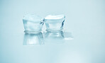 Two ice blocks melting side by side against a blue background in studio. A symbol of global warming as an environmental risk and concern. UV protection is needed during the hot season of summer