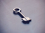 Closeup of a metal key isolated on a dark background or grey table. Get access to a new home whether buying, selling or renting. Security, safety and real estate