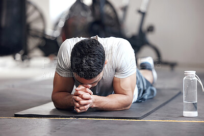 Buy stock photo One exhausted young hispanic man taking a break while struggling to exercise in a gym. Muscular mixed race man looking tired, disappointed and ready to quit after intense training and challenging workout. Overtraining can lead to injury and muscle pain