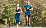 Fit young man and woman running together outdoors. Interracial couple and motivated athletes doing cardio workout while exercising for better health and fitness at the park