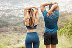 Fit young man and woman from the back stretching arms and triceps by pulling elbow with hands towards spine behind head while exercising outdoors. Two athletes doing warmup to prepare body and muscles for training workout or run