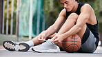 Basketball player, shoes and sports in preparation for game, match or fitness on the court outdoors. Man on basketball court tying shoe laces getting ready or prepare for exercise or training workout