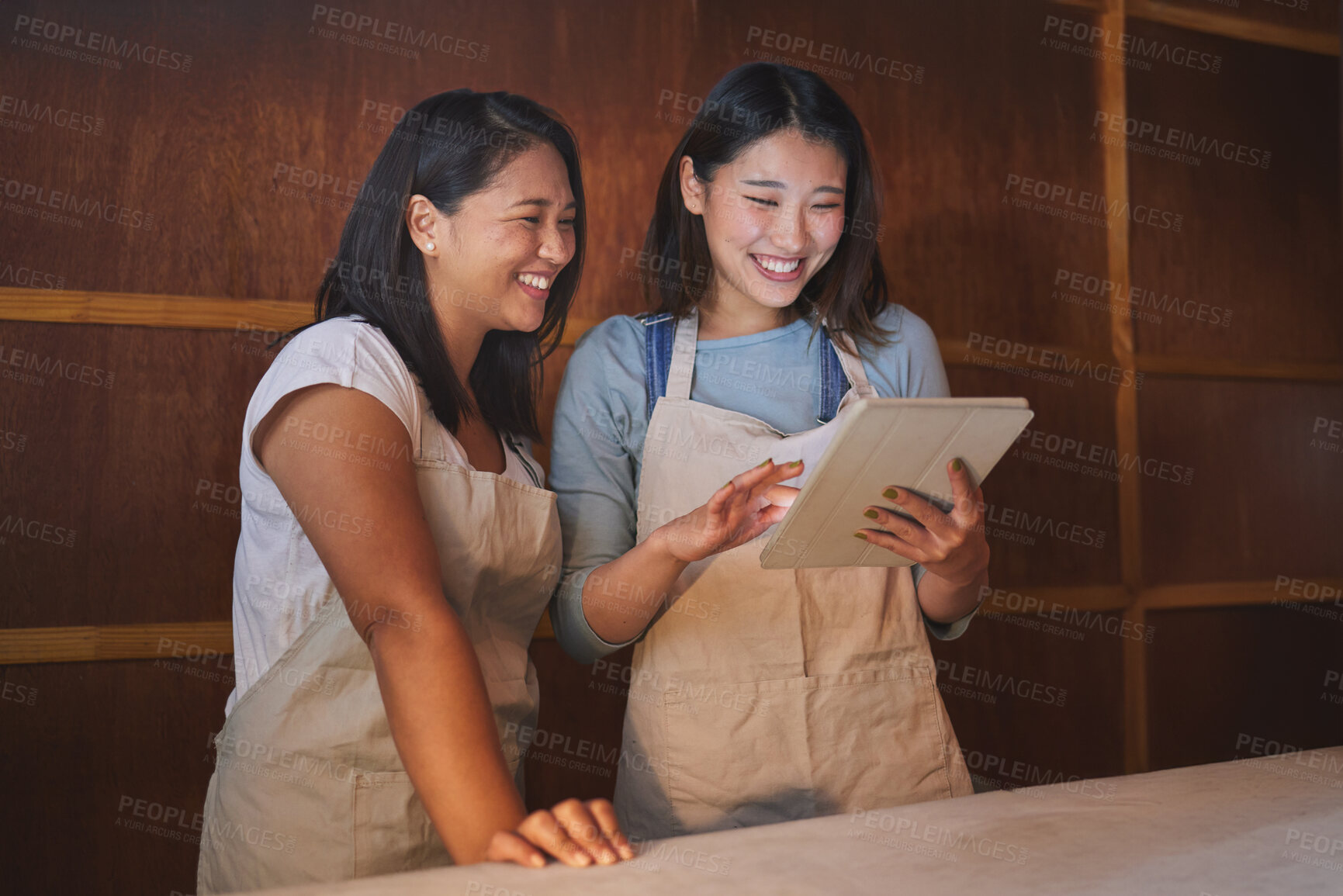 Buy stock photo Restaurant, tablet and happy asian women at counter together checking sales, booking or menu for small business. Social media, food review and startup cafe owner with waitress scroll on digital app.