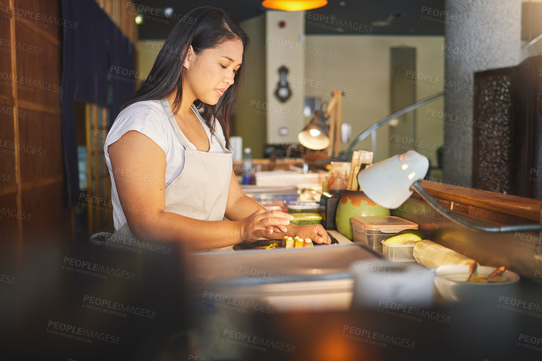 Buy stock photo Chinese food, cooking and an asian woman in a sushi restaurant to serve a traditional meal for nutrition. Kitchen, recipe and preparation with a young chef in an eatery for fine dining cuisine