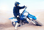 Dirt, motorbike and athlete driving in sports, adventure or man in desert, sand and riding outdoor on dune in nature. Extreme sport, bike or motorcycle drive with helmet, gear or person with freedom