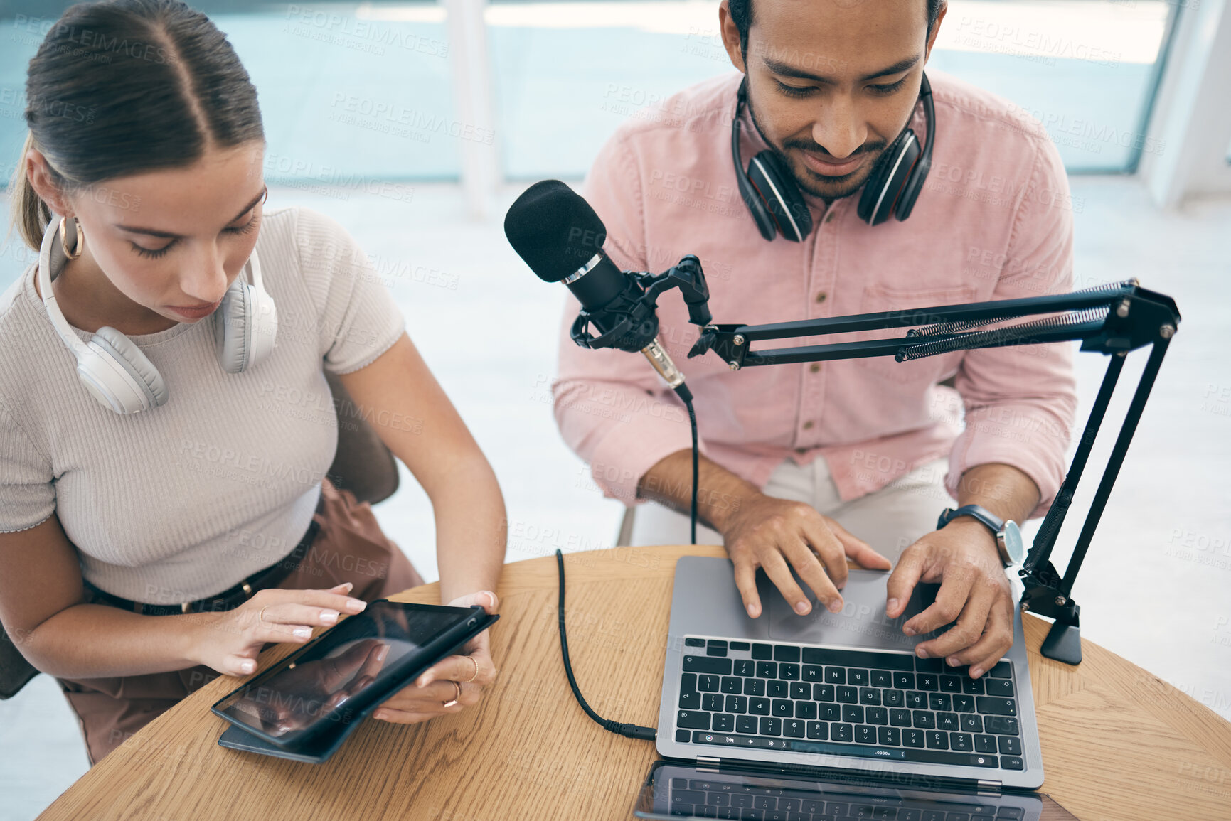 Buy stock photo Radio presenter, technology and teamwork for podcast, content creation and planning with laptop or tablet. Talk show, man and woman in studio with headphones for collaboration with broadcast or media