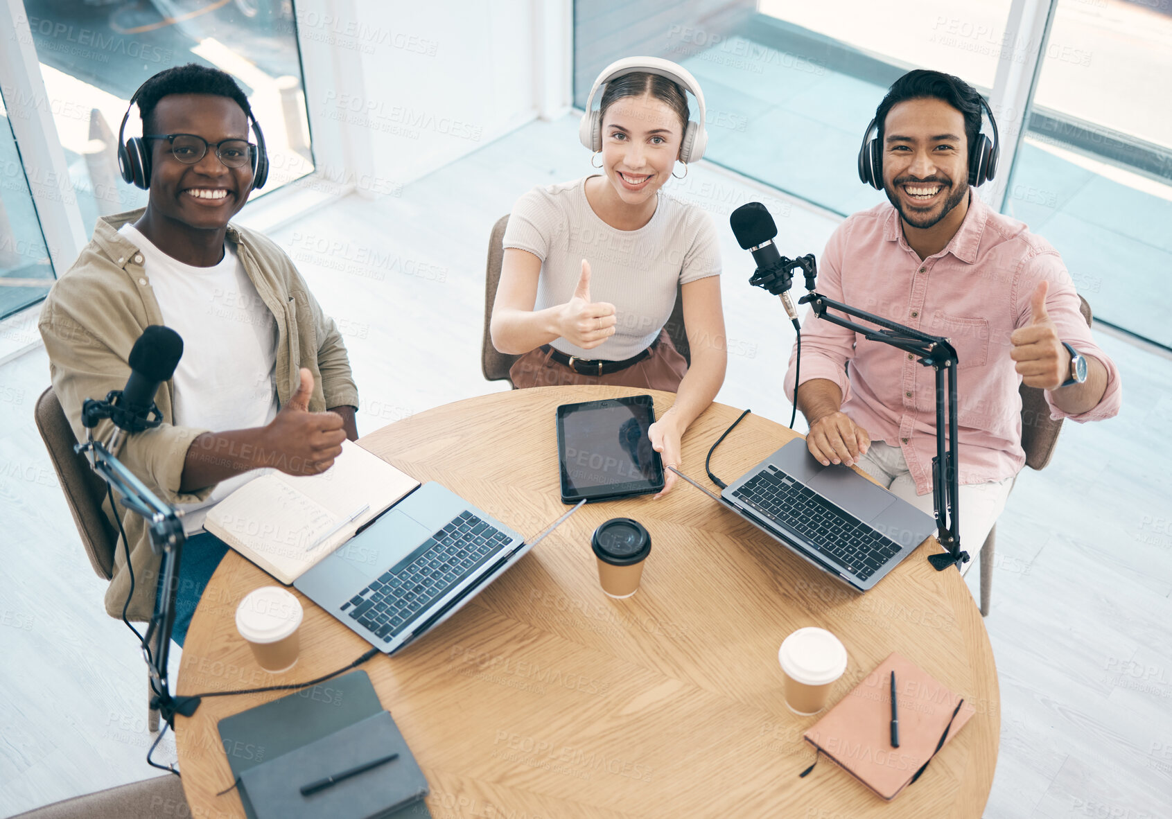 Buy stock photo Thumbs up, people in radio and hosting talk show, broadcast and content creation with people in portrait. Headphones, laptop and mic, podcast success and influencer with top, hand gesture and media