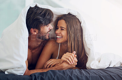 Buy stock photo Couple, smile and under blanket in bed for morning romance, love and bonding on weekend. Relationship, man and woman laying together in home for comfort, relax or care and playing with partner