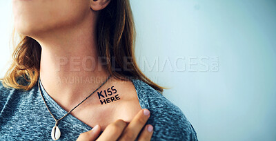 Buy stock photo Tattoo, words or person with design on body or shoulder for unique creative style in studio on blue background. Identity, neck or kiss here text with ink on skin for creativity or artistic expression