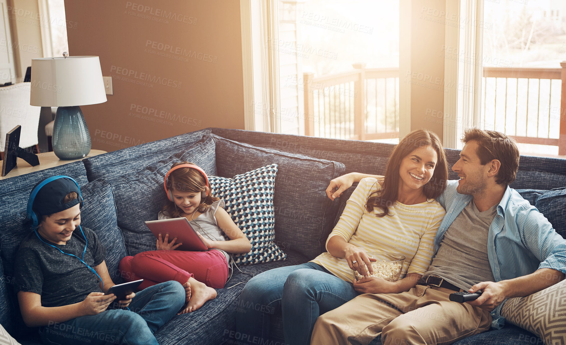 Buy stock photo Family, children and parents with popcorn, sofa and streaming on tablet with bonding in living room. Woman, man and kids with headphones, happy and watching tv to relax with film on couch at house