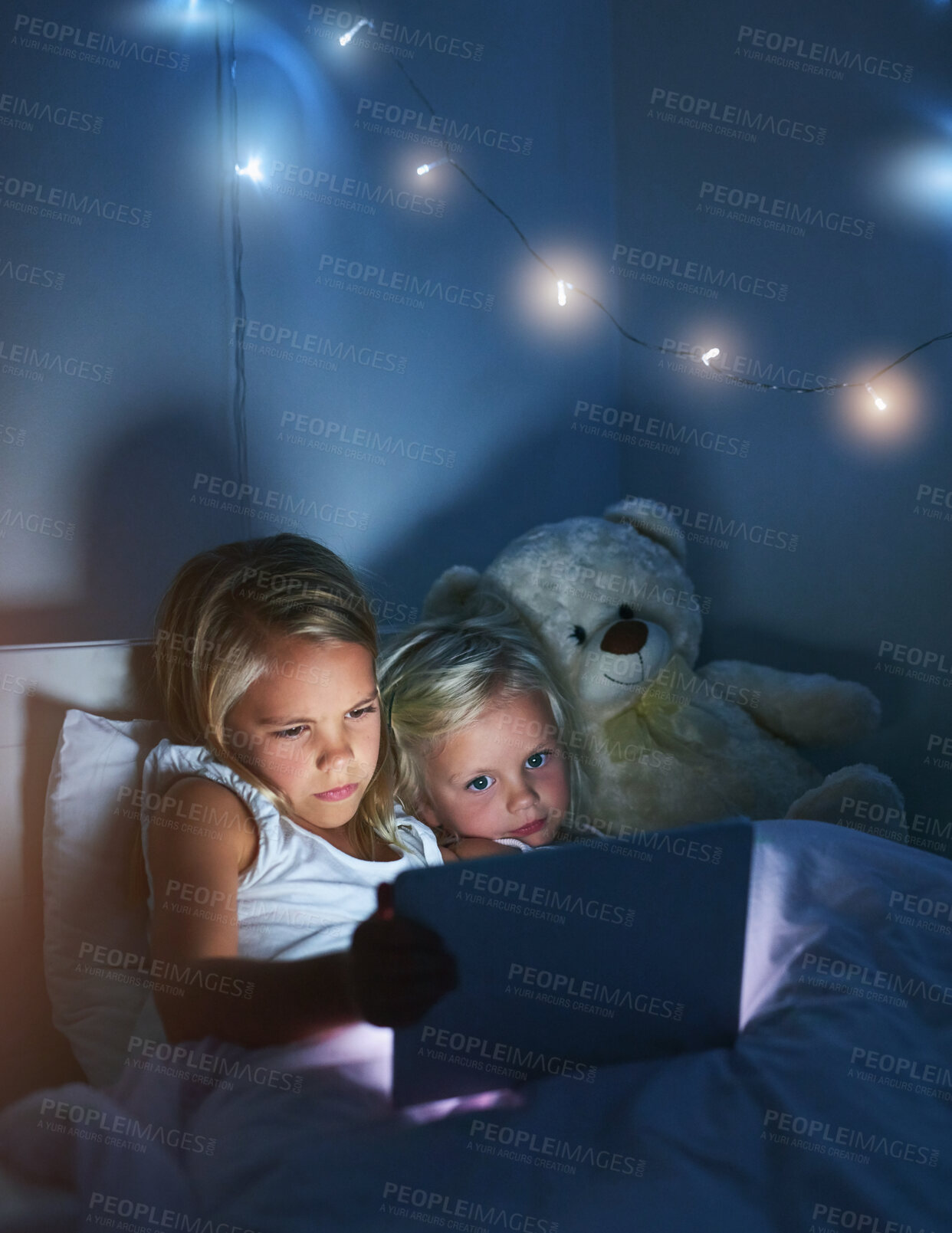 Buy stock photo Tablet, bedroom and children in home at night for streaming movie, video or cartoon together. Digital technology, girl or kids in bed for game or sisters reading story online to relax with teddy bear