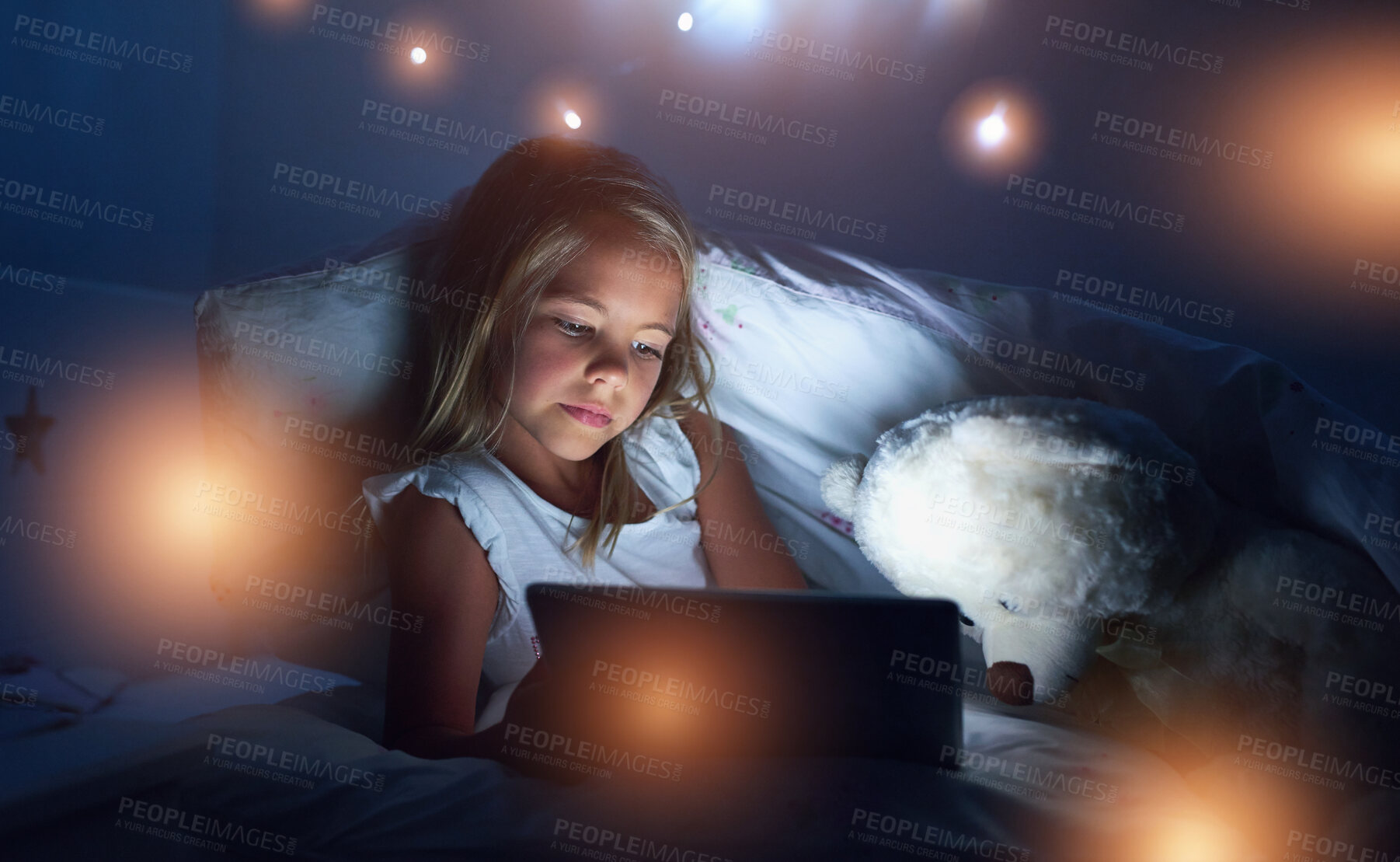 Buy stock photo Tablet, bedroom and child in home at night for streaming movie, video or cartoon with light. Digital technology, girl or kid in bed for game, internet or reading story online to relax with teddy bear