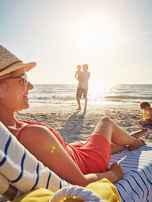 Buy stock photo Woman, smile and relax on chair at beach with family playing   sand, adventure and bonding in summer holiday. Happy, mother and resting by ocean, travel and freedom for tropical vacation in Greece